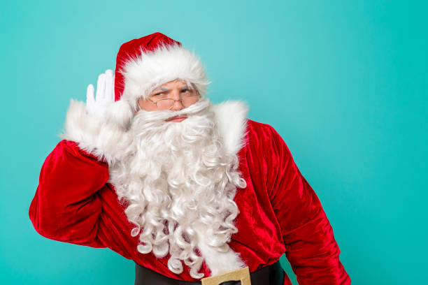 istock Santa holding hand next to ear listening 1191501635