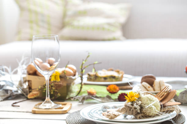 The interior of the room with a festive Easter table .A large white wooden table with a festive cake and Golden Easter eggs . The concept of a family celebration. Easter holiday.