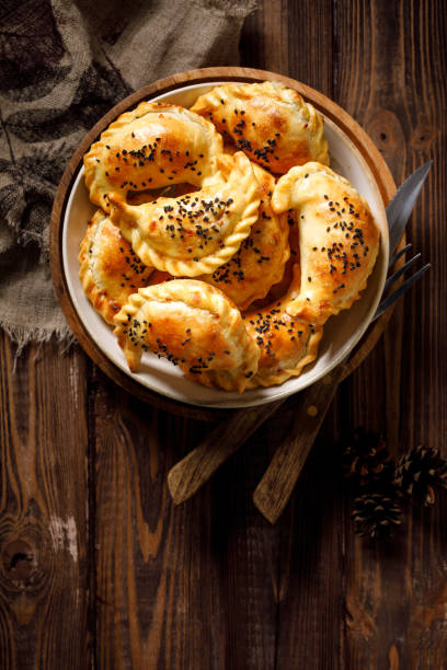 istock Baked dumplings (pierogi) with mushroom stuffing in a ceramic bowl on a wooden table 1191503398