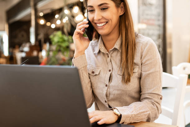 istock Gorgeous young caucasian woman talking on her smart phone while browsing on her laptop in a coffee shop. 1191505080