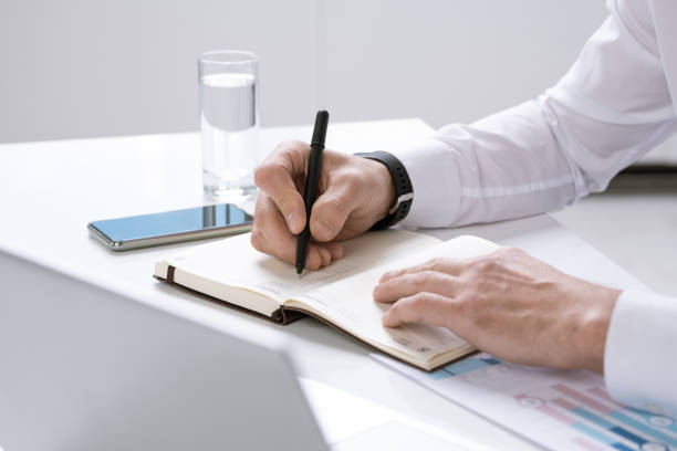 istock Hands of busy contemporary entrepreneur with pen over page of notebook 1191507708