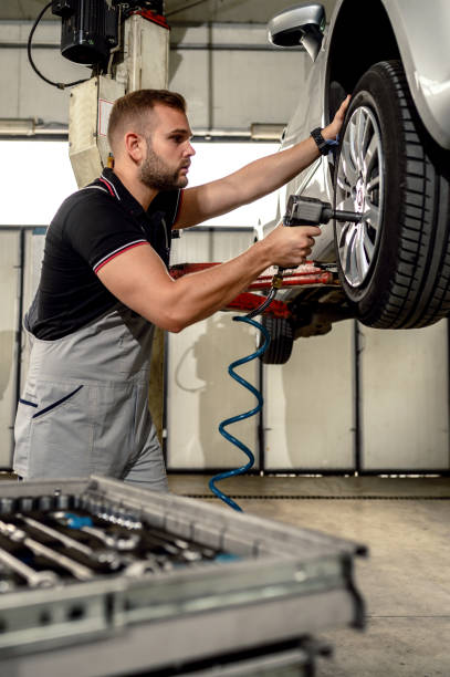 car mechanic is changing tire - automobile industry transportation indoors vertical imagens e fotografias de stock