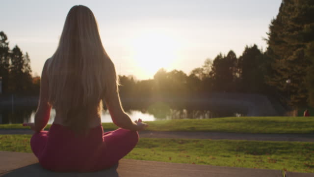 Woman Sitting in Lotus Pose Zen Posture Meditating For Wellness Sunny Golden Hour Backlight