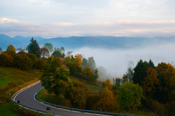full autumn with fog, yellow and red foliage in the meadows on the Asiago plateau, with the melettes in the background and the ossuary in the distance