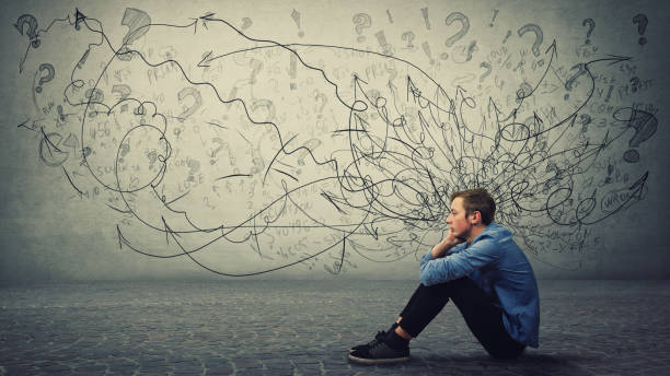 Upset and tired boy teenager sitting on the floor keeps hand to cheek looking thoughtfully and hopeless. Stressed student guy feels emotional discomfort, anxiety and mental health problems. Upset and tired boy teenager sitting on the floor keeps hand to cheek looking thoughtfully and hopeless. Stressed student guy feels emotional discomfort, anxiety and mental health problems. emotion stock pictures, royalty-free photos & images