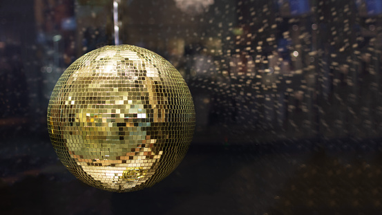 Golden mirror disco ball with bright golden rays, night party background photo with copy space.