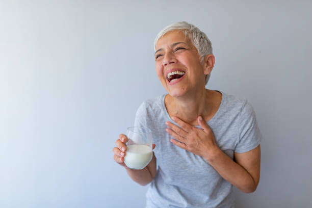 allegra donna matura che si diverte mentre beve latte. - mature women beautiful senior women menopause foto e immagini stock