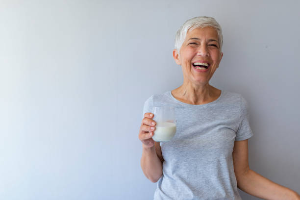 istock Happy senior woman having fun while drinking milk at home. 1191511735