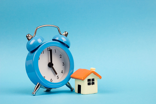 clock and miniature house on a blue background, , copy spaсe