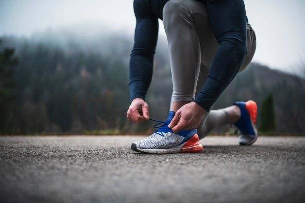 atleta ateando el cordón de zapatos al aire libre. - cordón fotografías e imágenes de stock