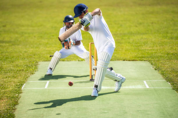 battitore di cricket che colpisce la palla mentre il wicket-keeper sta dietro di lui. - battitore del cricket foto e immagini stock