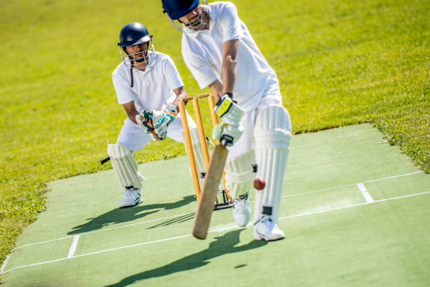 Cricket batter hitting the ball Cricket batsman hitting the ball with the wicket and the wicket-keeper standing behind him. cricket stock pictures, royalty-free photos & images