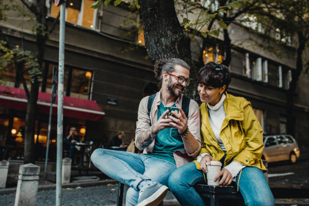 istock Two friends sitting outdoors and looking at smart phone 1191514995