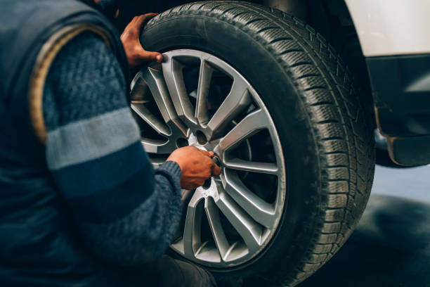 mecânico que muda a roda de carro na oficina de auto. mecânico que ajusta a roda de pneu usando a mão e a ferramenta na garagem do carro do reparo - adjustable wrench fotos - fotografias e filmes do acervo