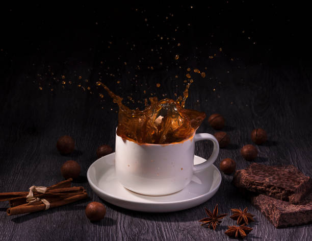 istock A cup with coffee splash with nuts and cinnamon stick on table wood over dark background 1191515981