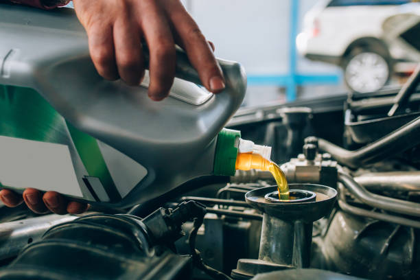 automechaniker arbeiten in der garage während der wartung des motors. mechaniker gießt frisches öl während reparatur eines autos in auto-service-garage - mechanician stock-fotos und bilder