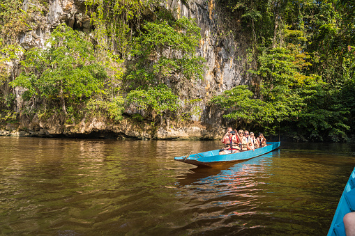 Small group of tourists on long boat on the river Melinau to the Clearwater Cave, Borneo islands