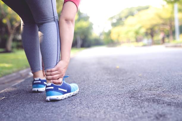 Woman is running causes leg pain in the park stock photo