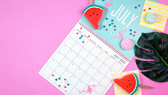 On-trend 2020 calendar page for the month of July modern flat lay with seasonal food, candy and colorful decorations in popular pastel colors. Copy space. One of a series for 12 months of the year.