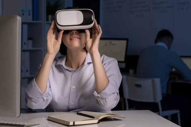 istock Young office worker with vr headset sitting by desk in front of computer 1191522132