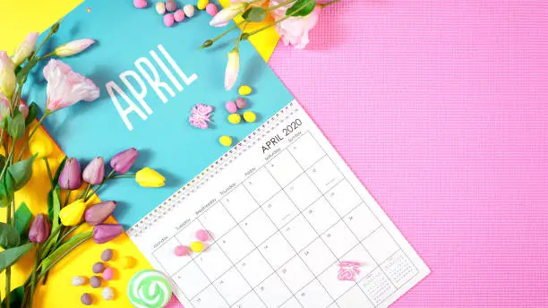 On-trend 2020 calendar page for the month of April modern flat lay with seasonal food, candy and colorful decorations in popular pastel colors. Copy space. One of a series for 12 months of the year.