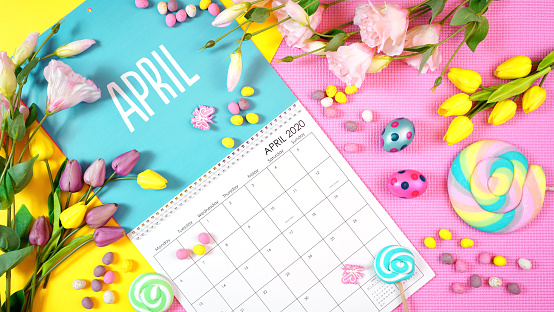 On-trend 2020 calendar page for the month of April modern flat lay with seasonal food, candy and colorful decorations in popular pastel colors. One of a series for 12 months of the year.