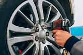 Mechanician changing car wheel in auto repair shop. Mechanic adjusting the tire wheel by using hand and tool at the repair car garage