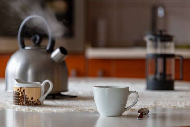 istock Coffee cup and metal kettle on the kitchen table. Morning coffee in the home kitchen. Light background. 1191524489