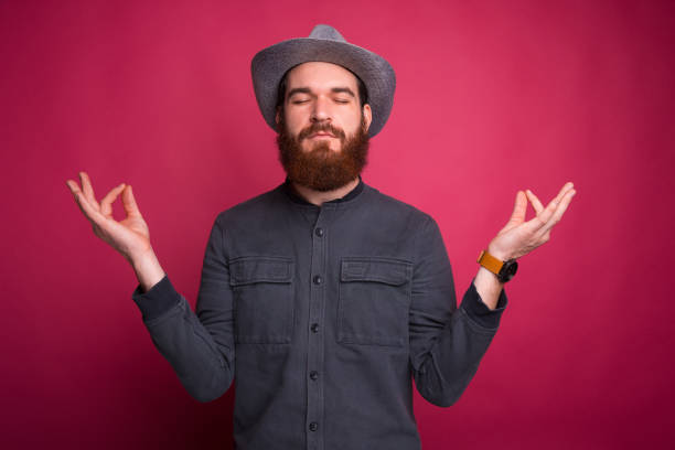 istock Bearded young man is doing zen gesture near pink wall. 1191524602