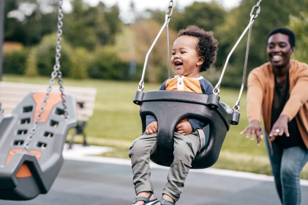 mama i maluch na placu zabaw - child swinging playground african descent zdjęcia i obrazy z banku zdjęć