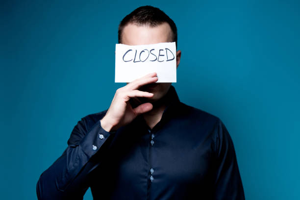 istock a man covers his face with a sign saying closed 1191528333