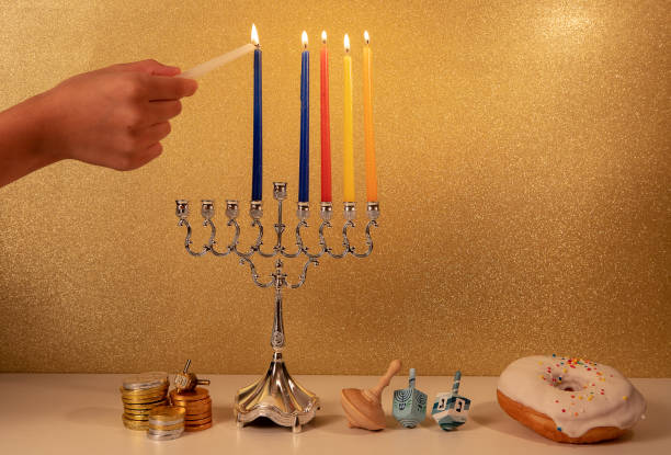 festa religiosa ebraica hanukkah con la mano del bambino che accende la 5a candela nel lampadario tradizionale menorah - hanukkah menorah human hand lighting equipment foto e immagini stock