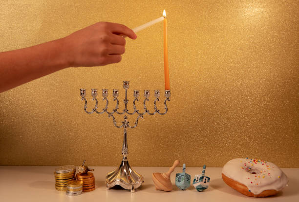 festa religiosa ebraica hanukkah con la mano del bambino che accende la prima candela nel lampadario tradizionale menorah - hanukkah menorah human hand lighting equipment foto e immagini stock