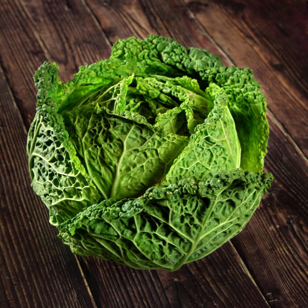 istock Single green savoy cabbage lettuce head on dark wooden board 1191540422