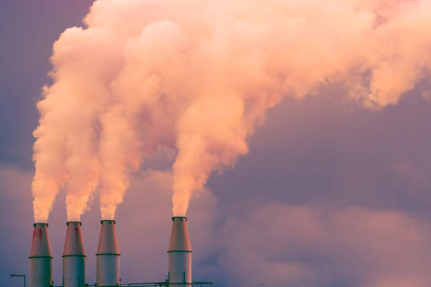 fumaça e vapor subindo no ar a partir de pilhas de usinas; nuvens escuras fundo; conceito para a poluição ambiental e as alterações climáticas - pollution smoke stack air pollution smoke - fotografias e filmes do acervo