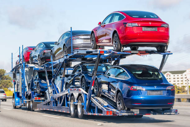 Car transporter carrying Tesla Model 3 new vehicles Aug 10, 2019 Burlingame / CA / USA - Car transporter carries Tesla Model 3 new vehicles on a freeway in San Francisco bay area, back view of the trailer; transporter stock pictures, royalty-free photos & images