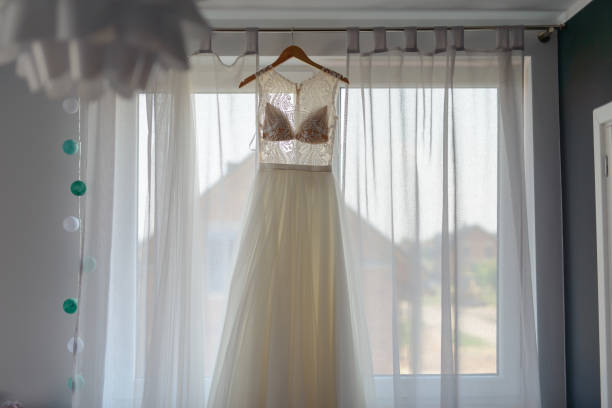 istock Bridesmaid helping slender bride lacing her wedding white dress, buttoning on delicate lace pattern with fluffy skirt on waist. Morning bridal preparation details newlyweds. Wedding day moments, wear. 1191549487