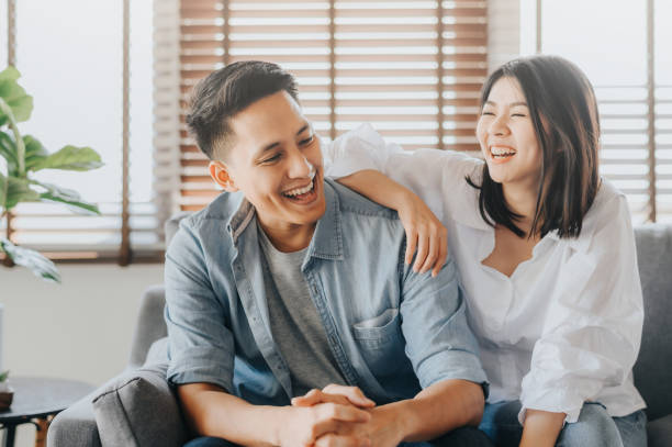 Asian couple having fun and laughing together Happy Asian couple having fun and laughing together in living room at home Laughing stock pictures, royalty-free photos & images