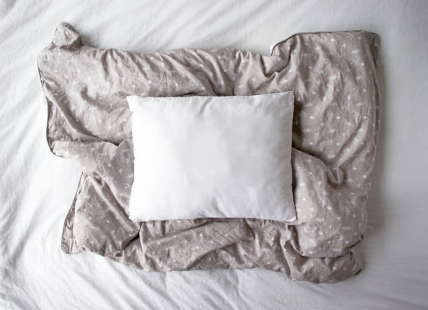 istock Blank white pillow lying on a grey patterned duvet cover - pillowcase mockup in natural light 1191559005