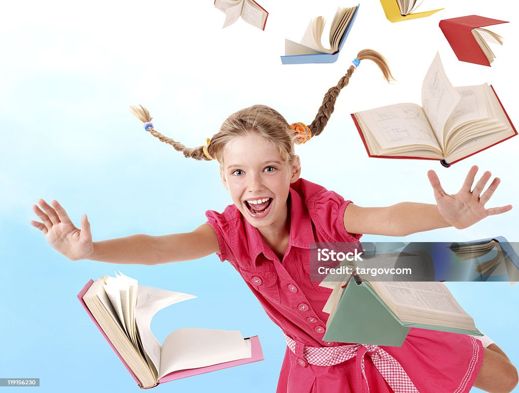 Smiling schoolgirl flying through a pile of books School girl  holding pile of books. Outdoor. Book Stock Photo