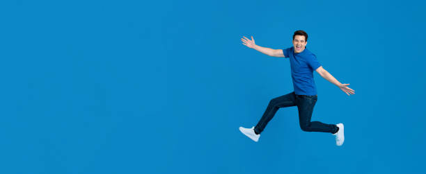 istock Energetic young man jumping and smiling with outstretched hands 1191566161