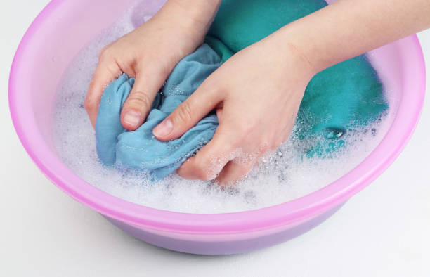 istock Female hands washing blue clothes in pink basin 1191571572