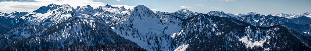 Amazing panoramic view of Washington mountains with snowy cliffs and ridges catching beautiful sunlight on crisp blue sky day