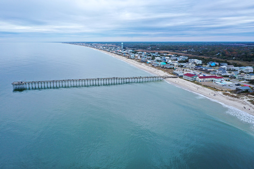 Aerial View of the Ocean Crest Pier at Oak Island NC. Over the water, looking back at the beach front past the pier.
