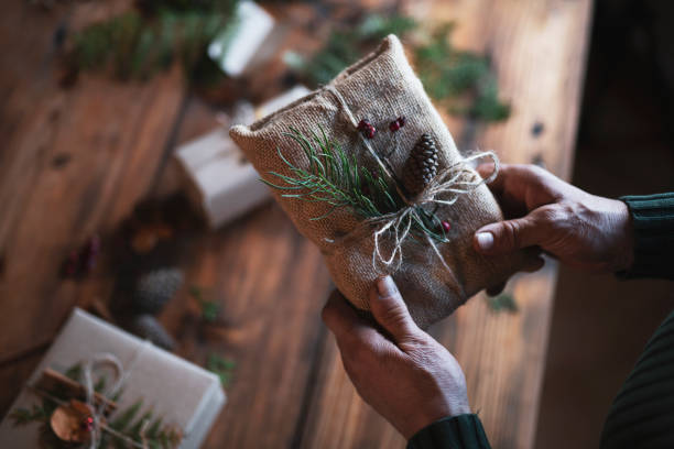 Preparing Christmas Gifts. Unrecognizable male hands wrapping Christmas presents with natural materials, plastic free, organic wrapping with paper. gift lounge stock pictures, royalty-free photos & images