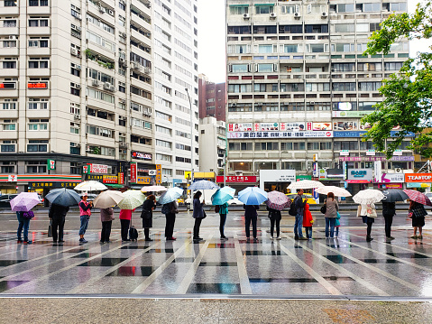 Taipei, Taiwan, May 2019: long line of people with umbrellas are standing waiting for the bus.