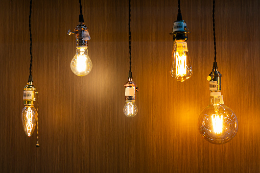 Decorative antique edison style light bulbs on wooden wall background.
