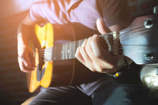 istock Close-up Man hands playing acoustic guitar with light flare. 1191580222