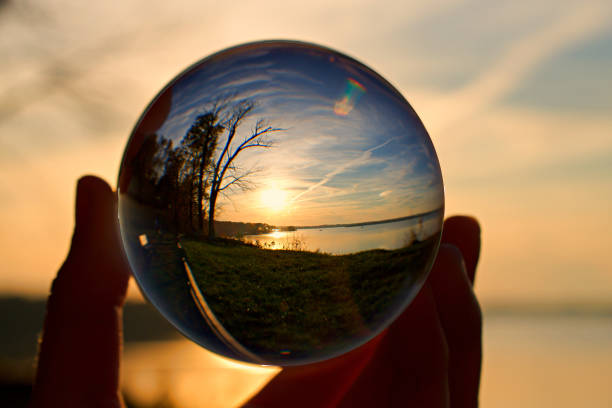 istock Reflection of sunset over water in a crystal ball, held by a hand 1191582040