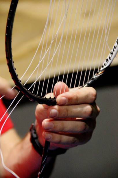 ajusta a tensão da corda da raquete do badminton, verticalmente. jovem repara uma raquete de badminton. sem pessoas - racket string - fotografias e filmes do acervo